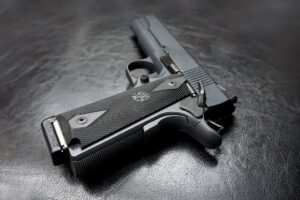 Black 9mm handgun lying on a black background. Pleasanton gun lawyers - Mirador Law